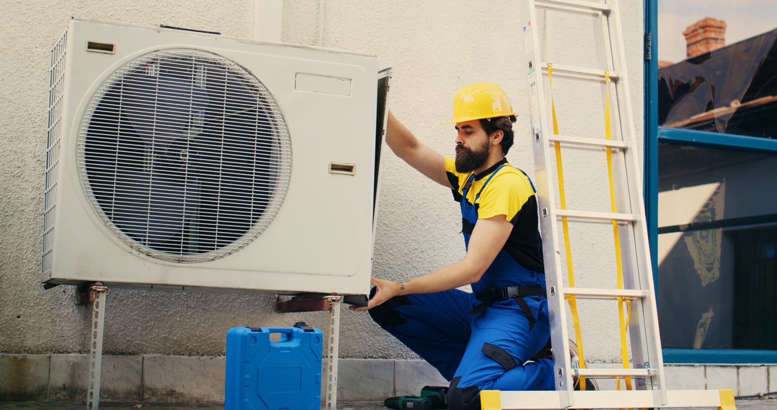 Professional worker starting work on malfunctioning air conditioner, using power drill to take apart condenser side coil panel. Capable electrician dismantling hvac system to check for faulty wires